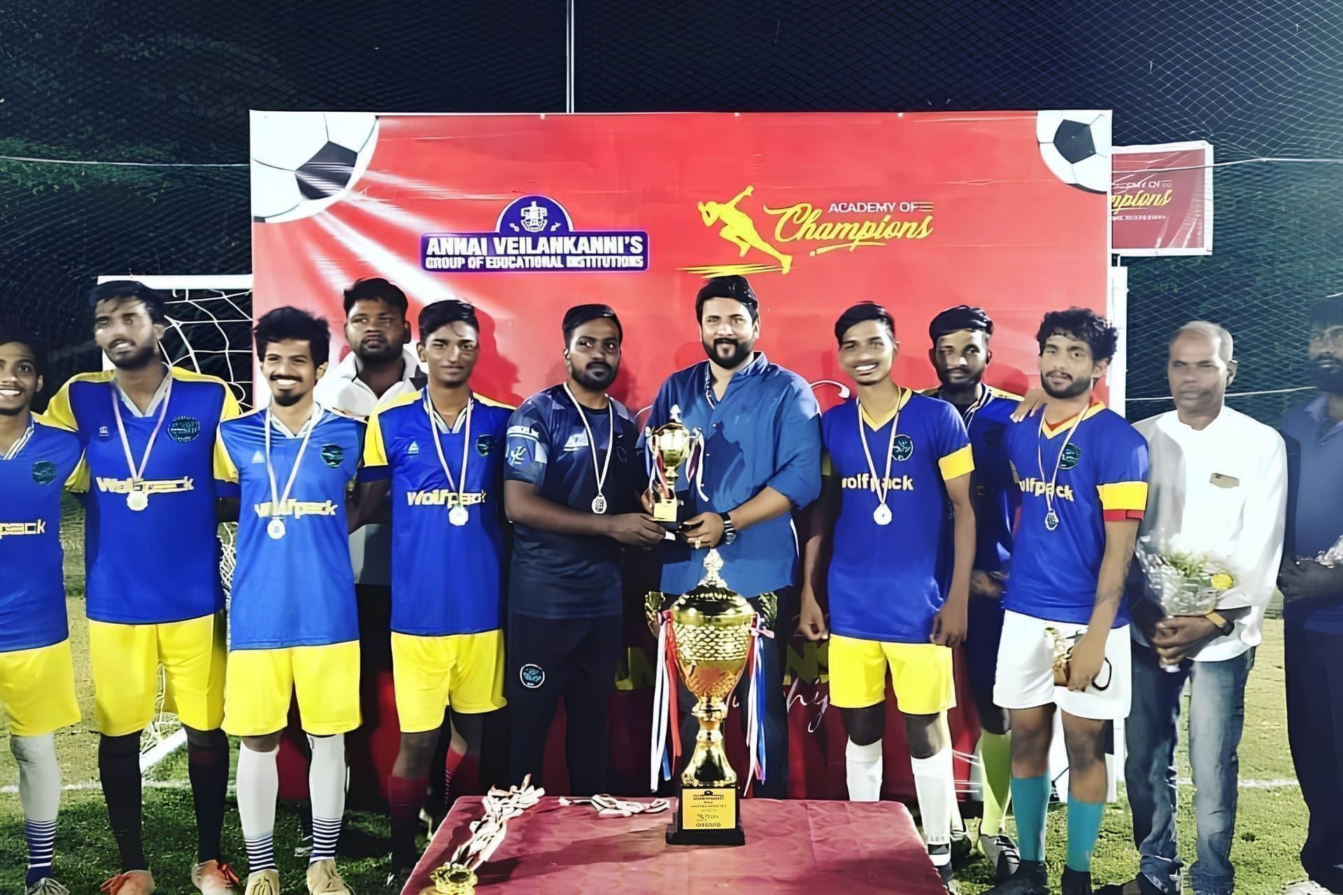 Cricket players in blue and yellow posing with trophies