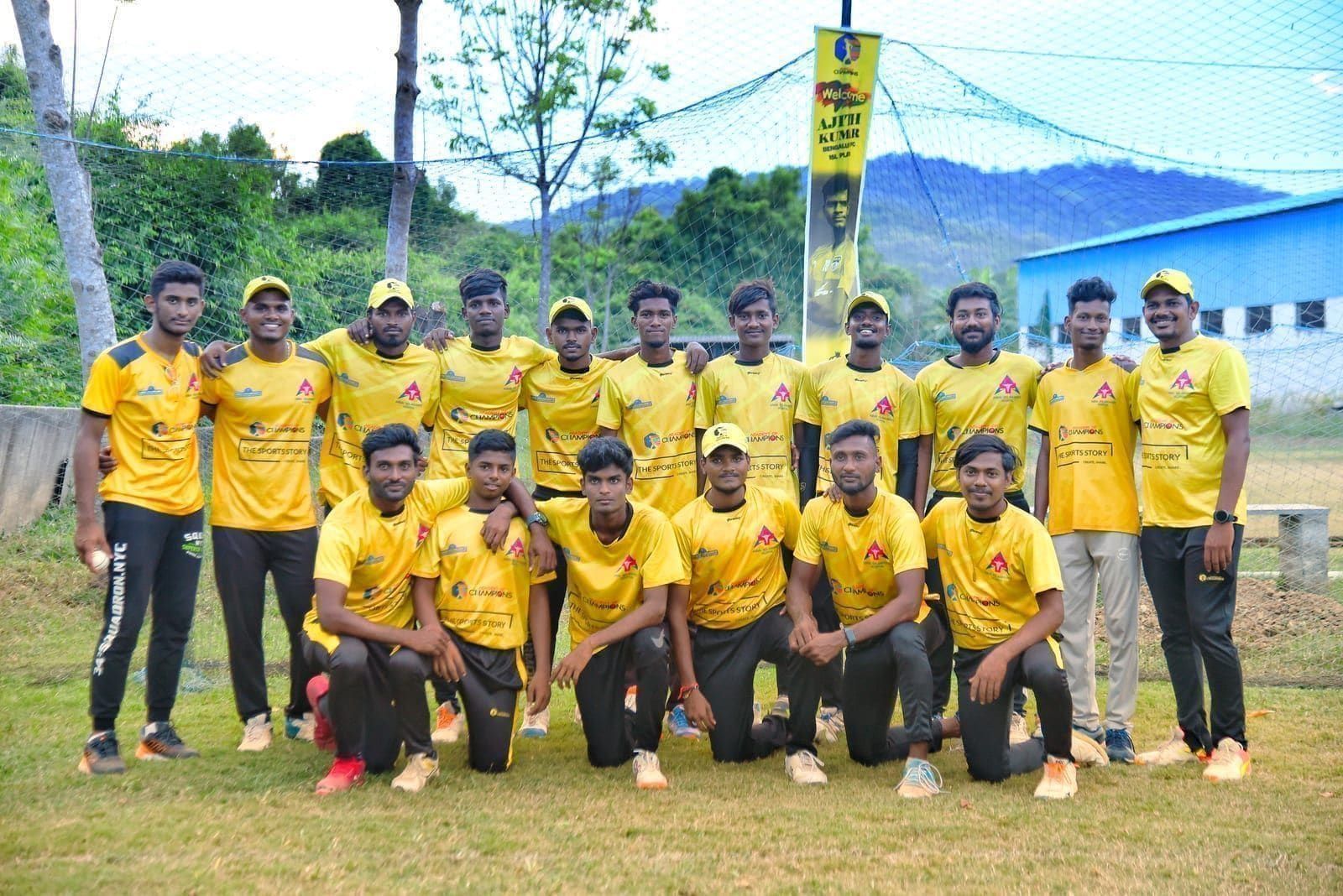 Players in yellow academy shirts posing beside the cricket nets