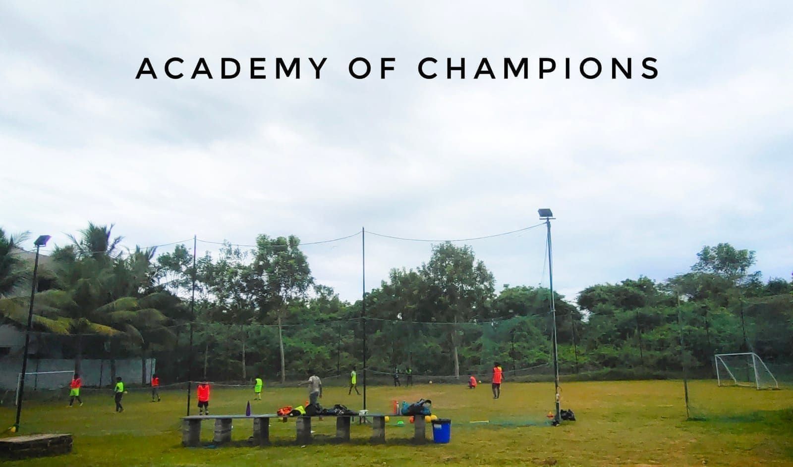 Academy players training on a grass field beside a goal