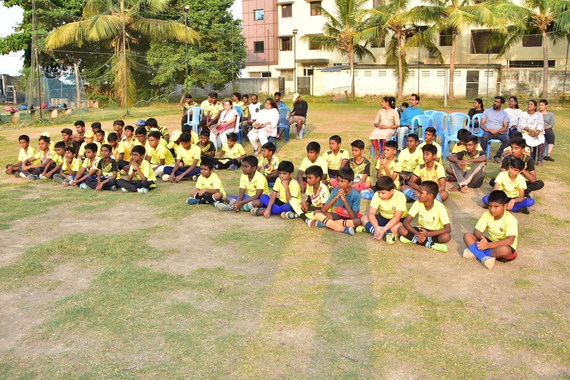 Academy players and adults seated together at the training ground