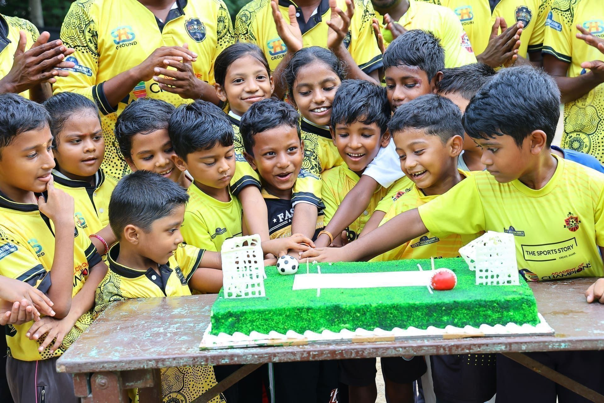 Academy juniors gathered around a cricket-themed celebration cake