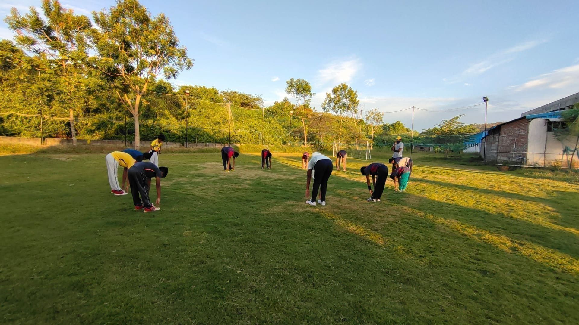 Young athletes stretching on the grass during an outdoor session