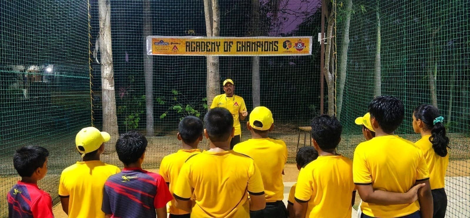 Coach speaking to young players inside the academy cricket nets