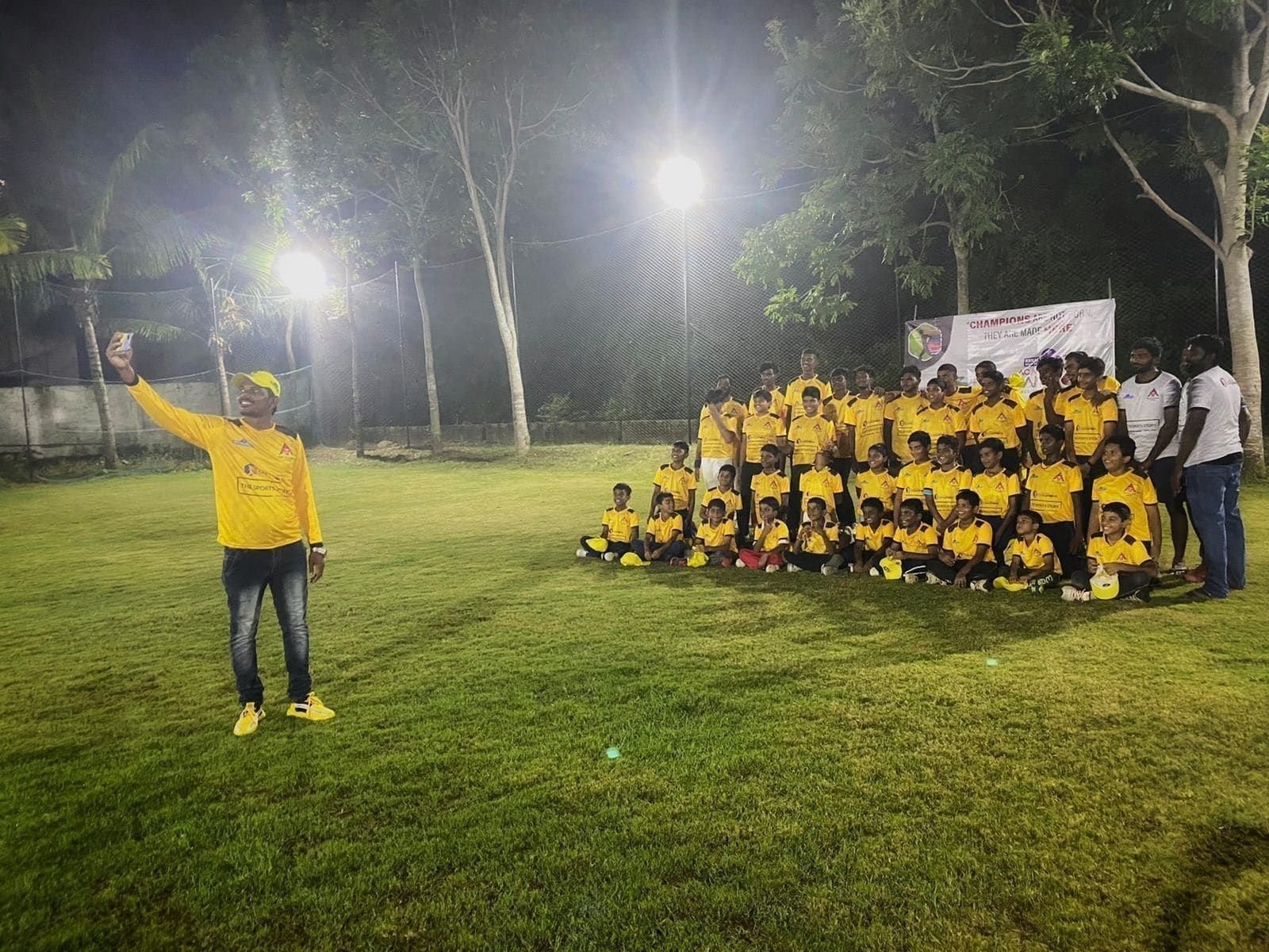 Coach addressing seated academy players under floodlights