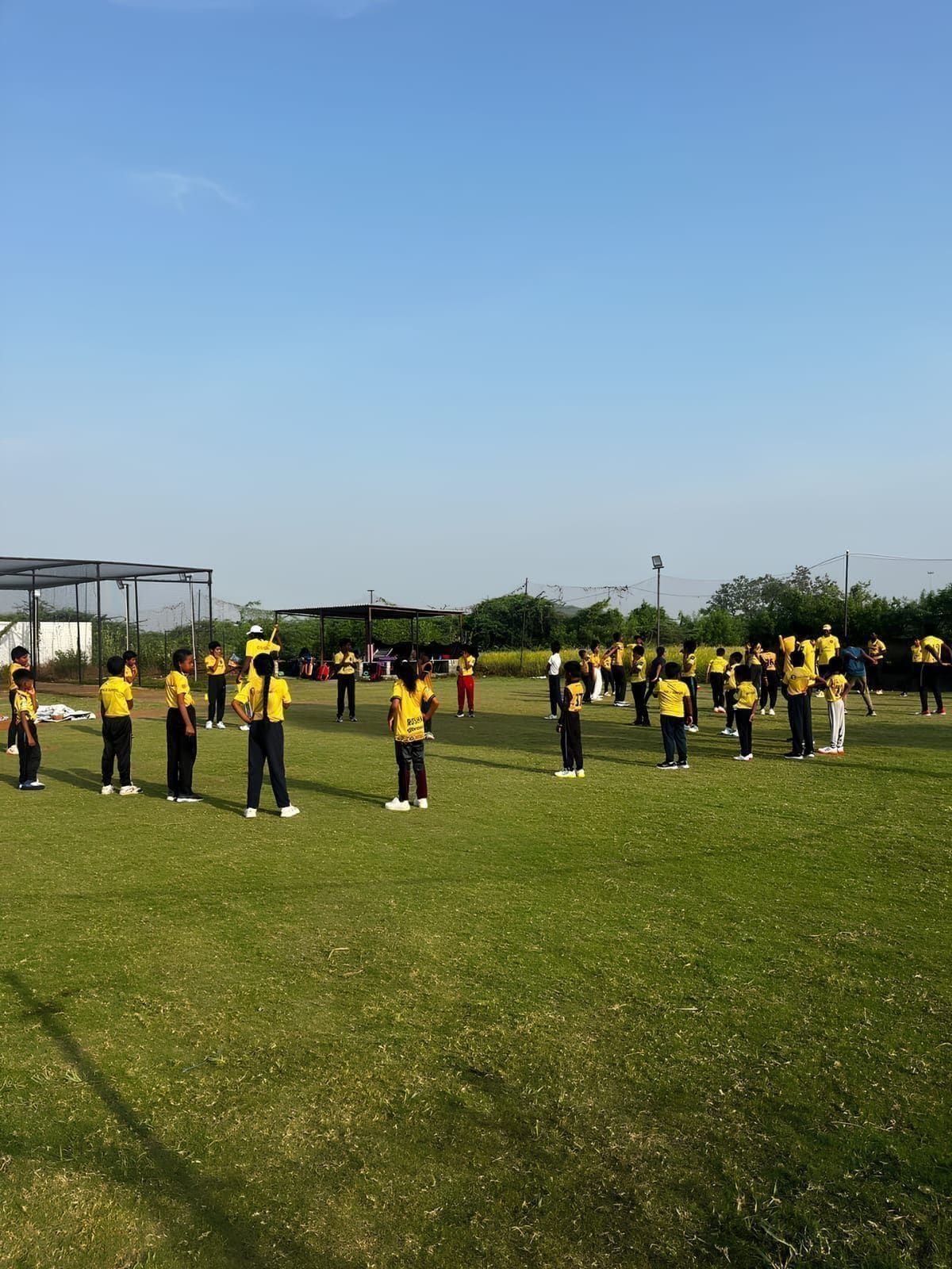 Players in yellow shirts lined up across a grass training field