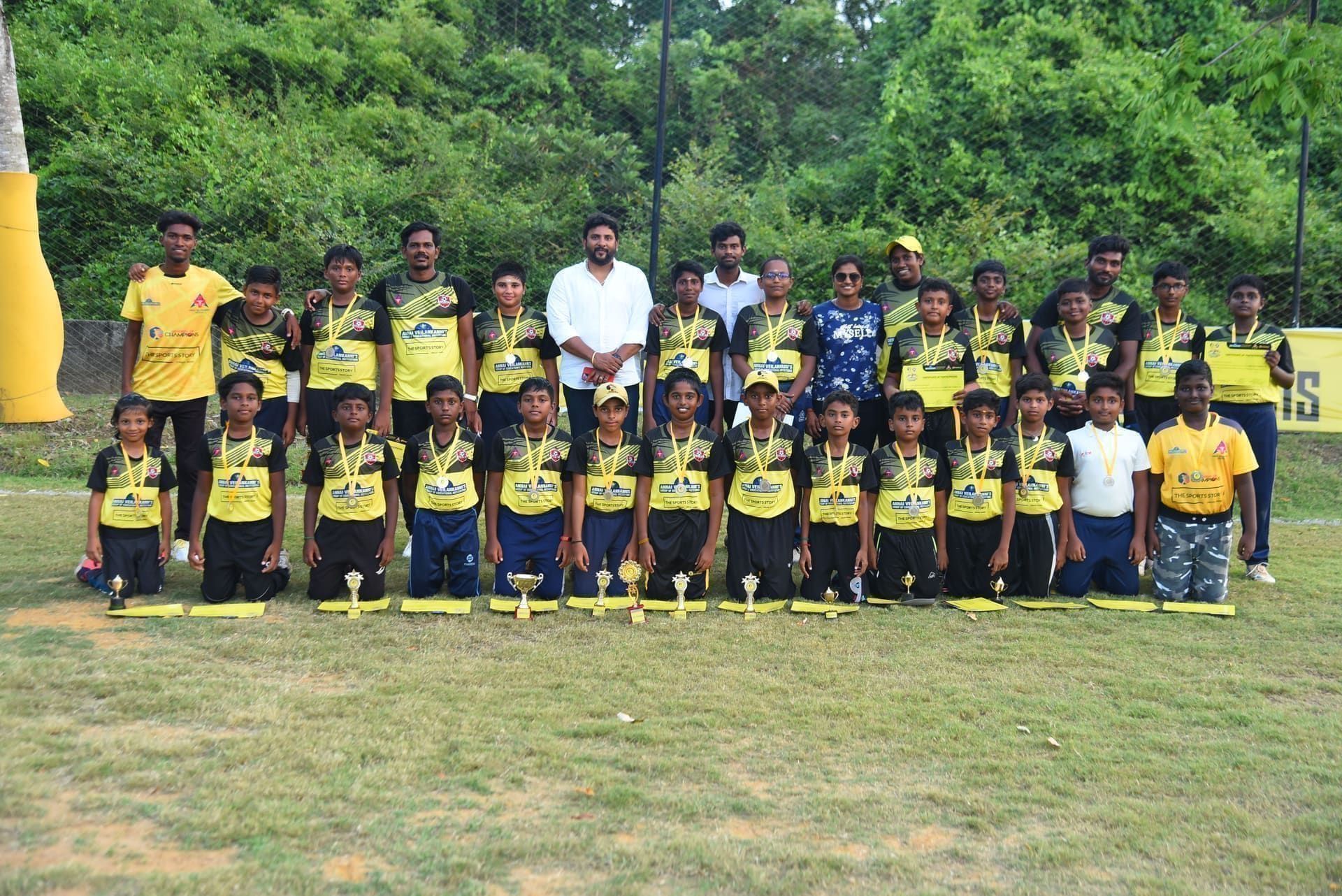 Junior players and coaches posing together beside the training field