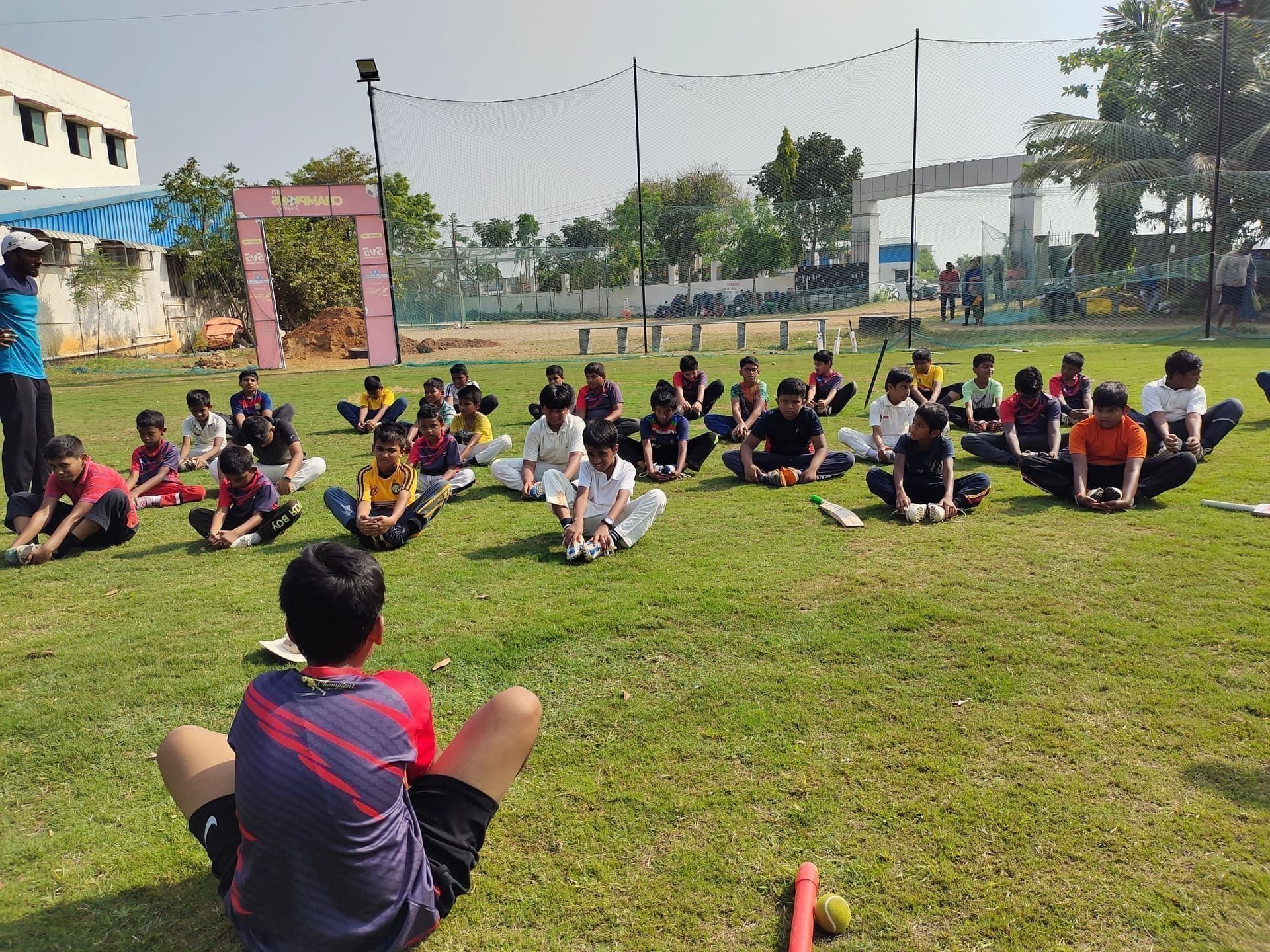 Coach speaking to players seated in a circle on the grass