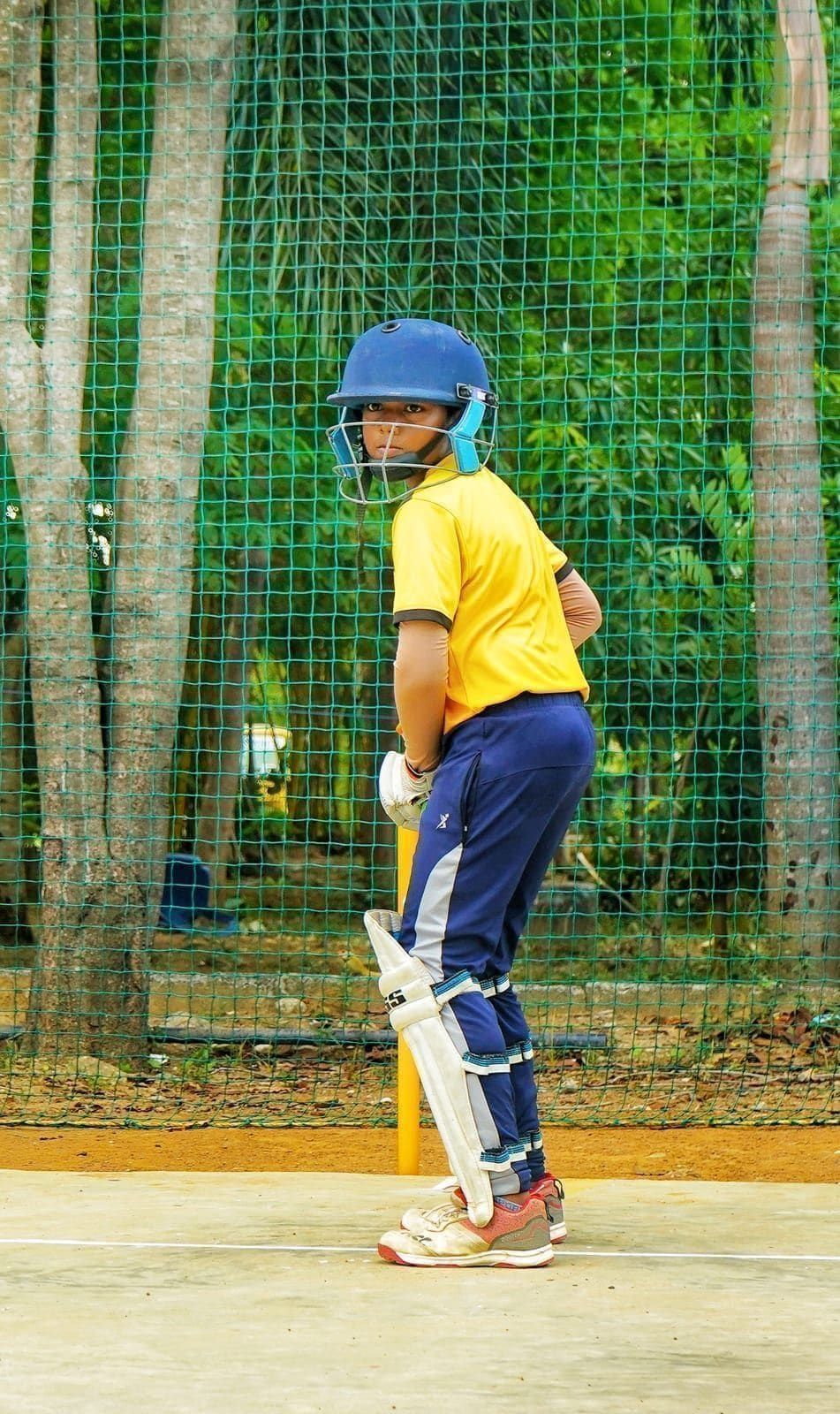 Junior cricketer in protective gear waiting at the stumps