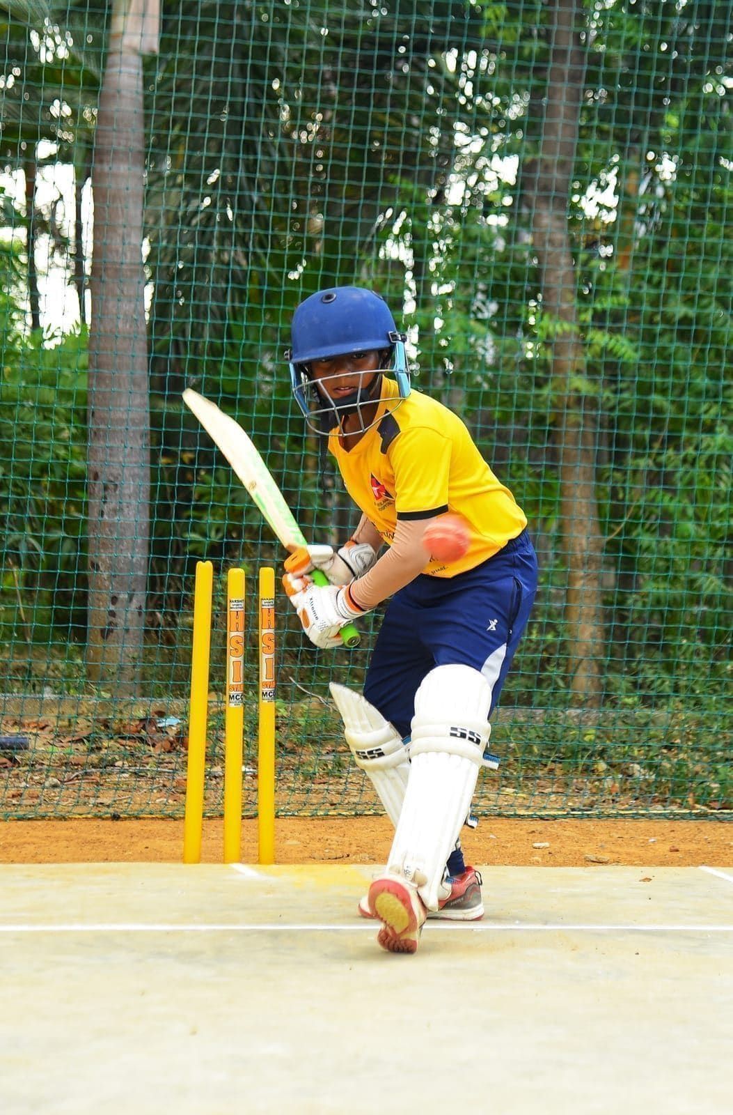 Junior batter in helmet and pads preparing to play a shot