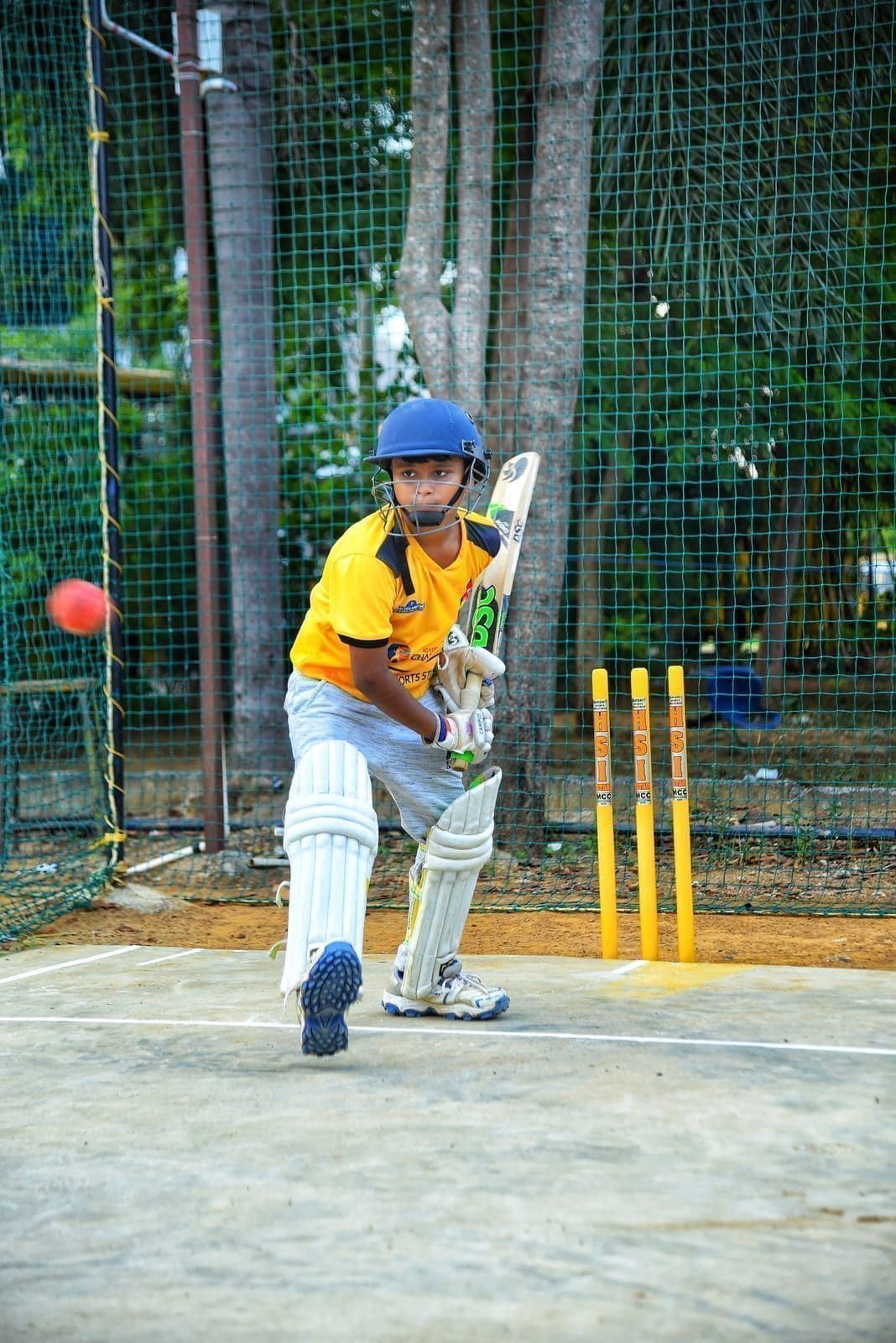 Junior batter stepping forward to play a ball at net practice