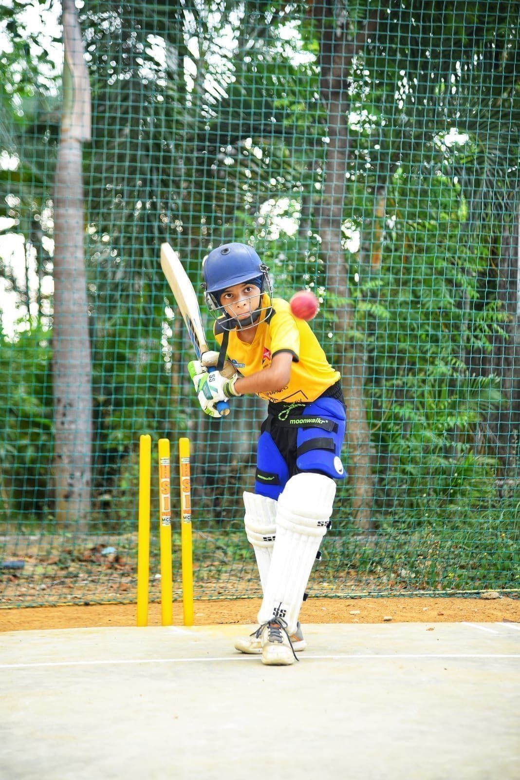 Junior batter following through on a shot inside the nets