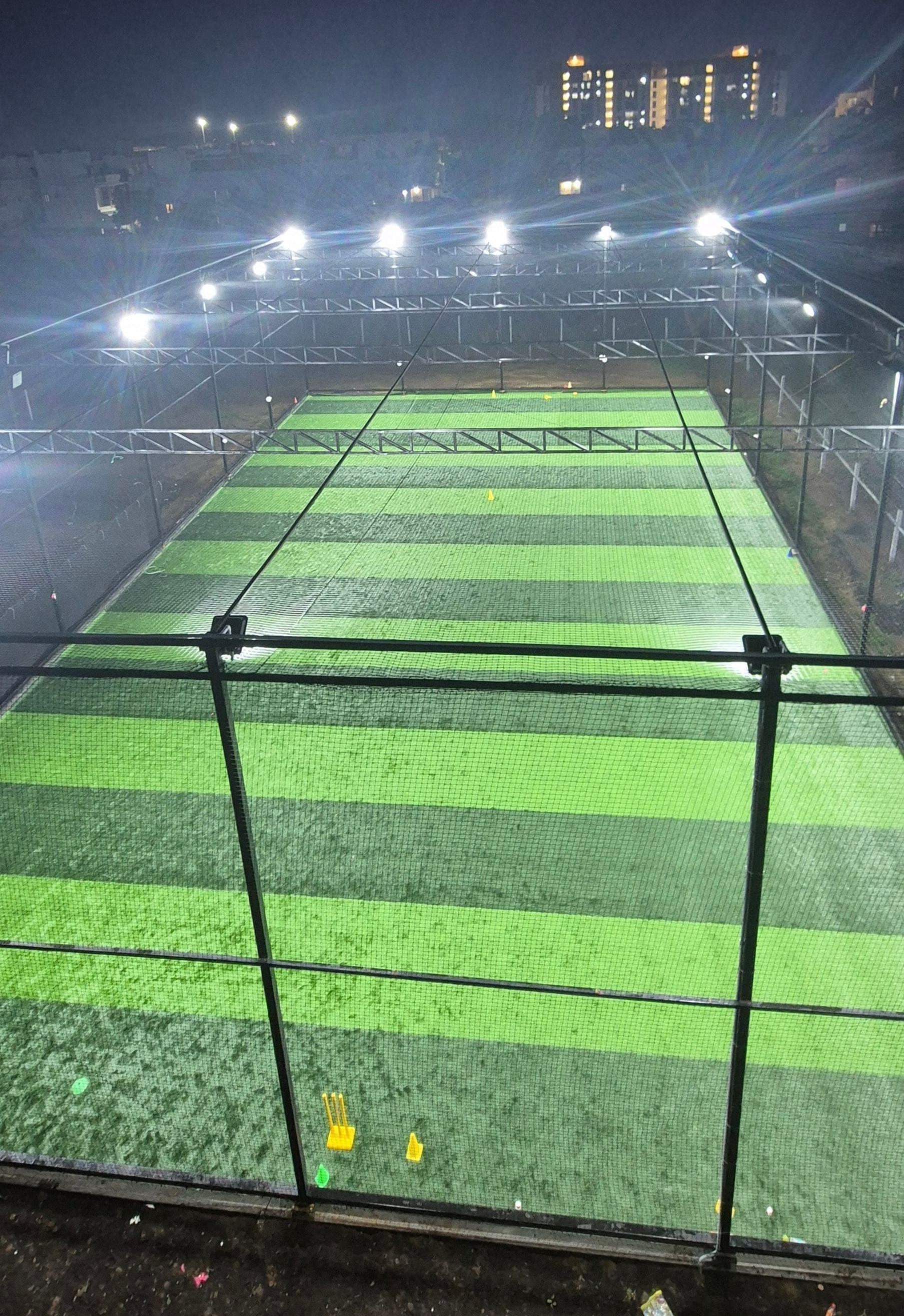 Empty floodlit academy turf and nets at night