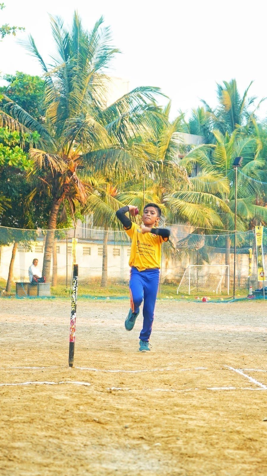 Young bowler working through a delivery beside practice stumps