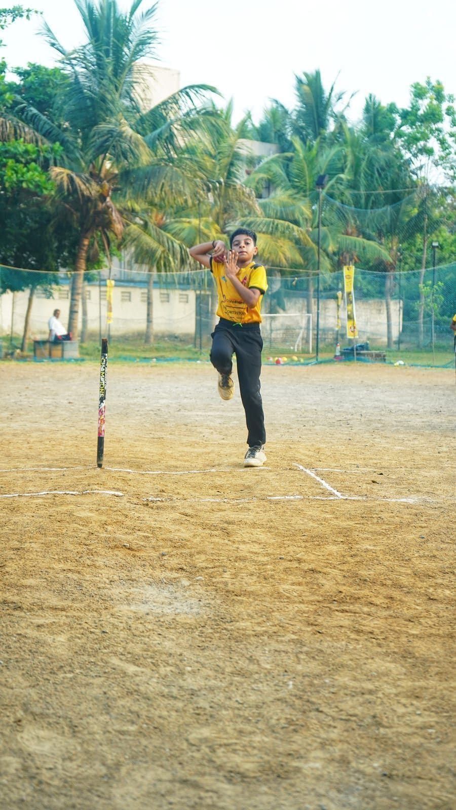 Young cricketer practising a bowling delivery on the field