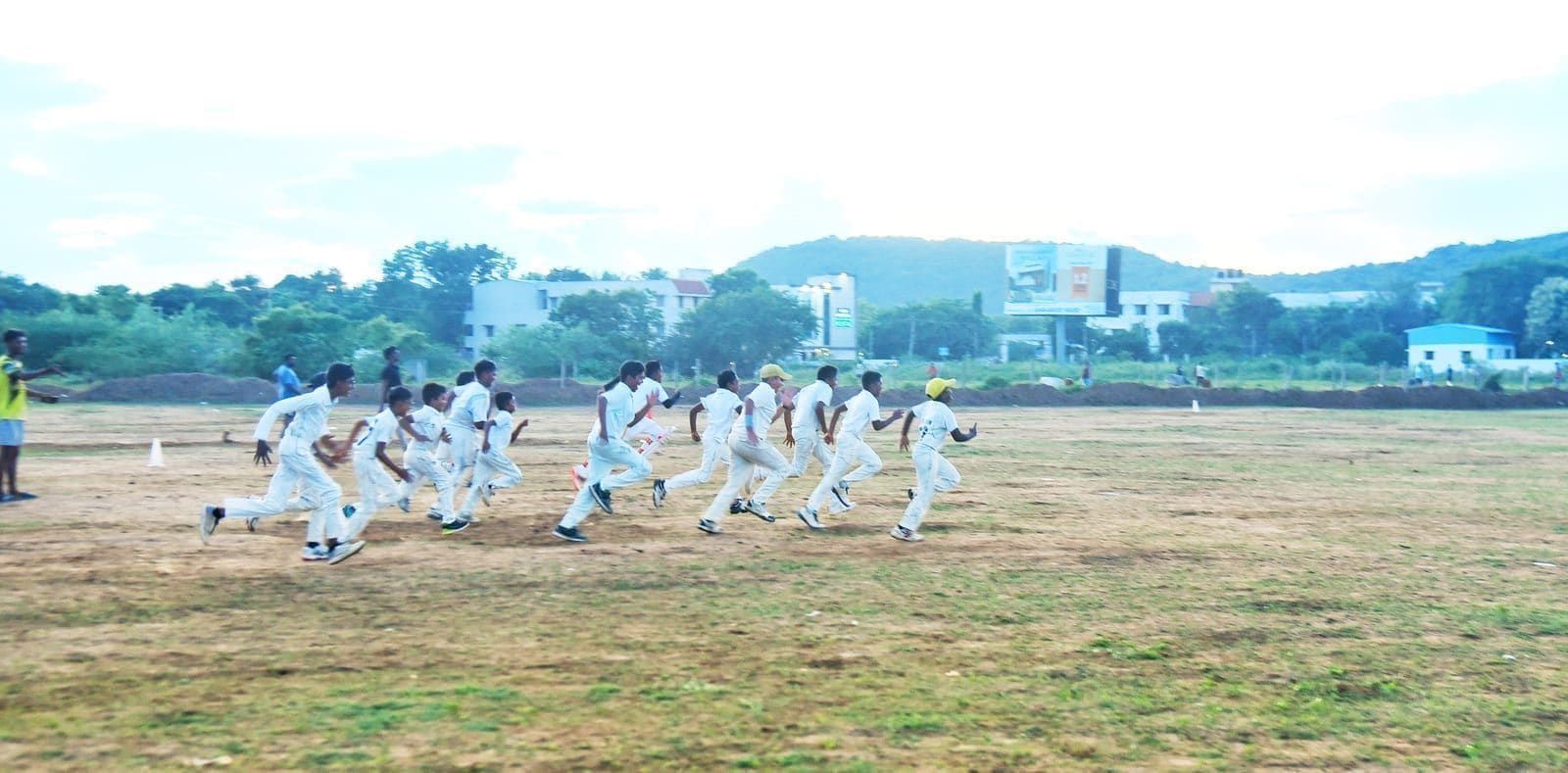 Junior cricketers running together across the outfield