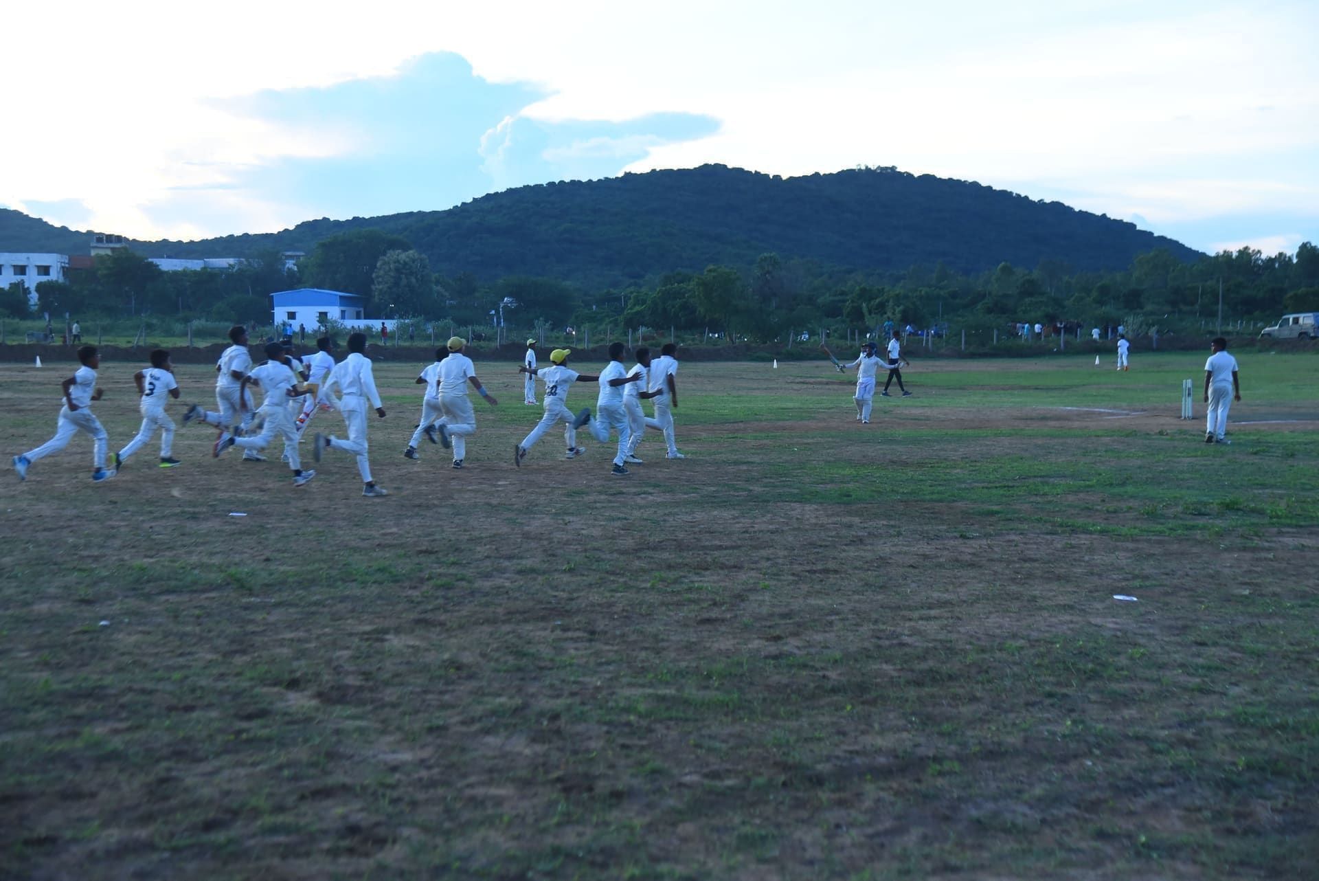 Players in cricket whites gathering on the field during a match