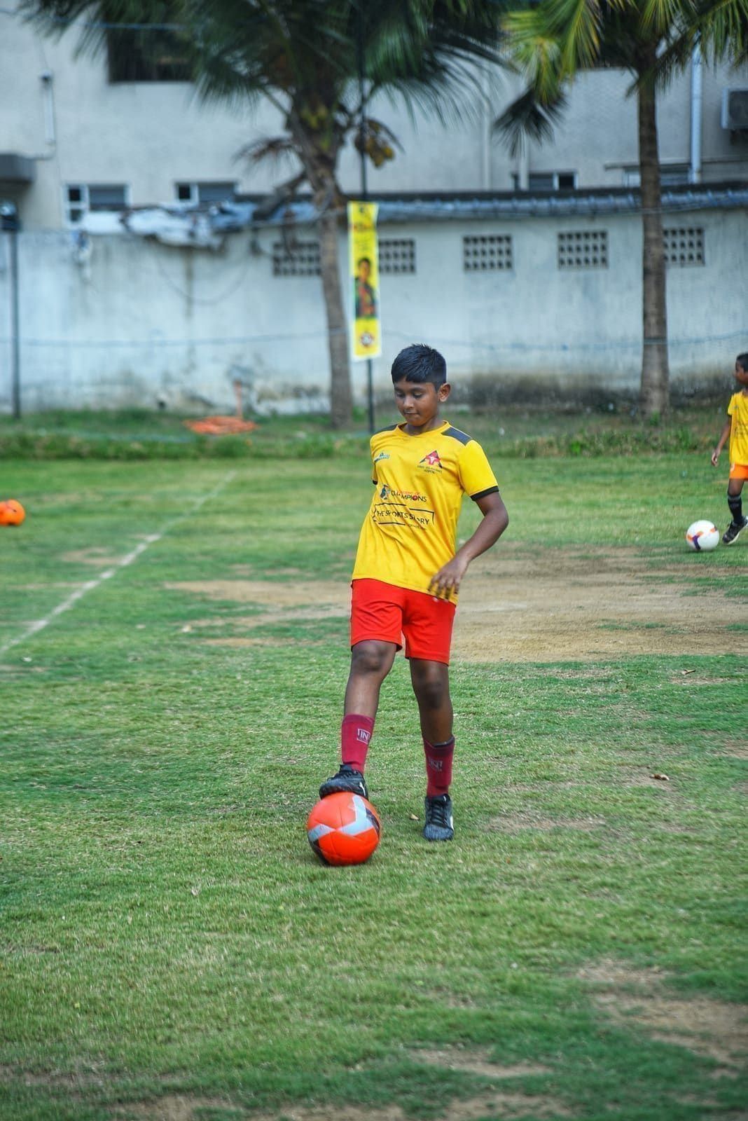 Young footballer controlling a red ball during practice