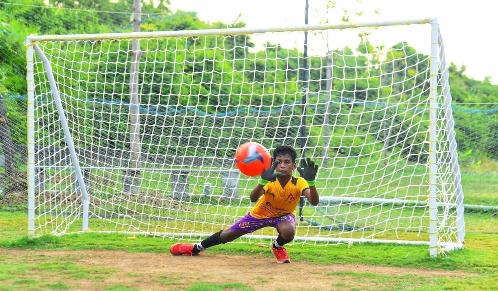Young goalkeeper reaching for a ball in front of the goal