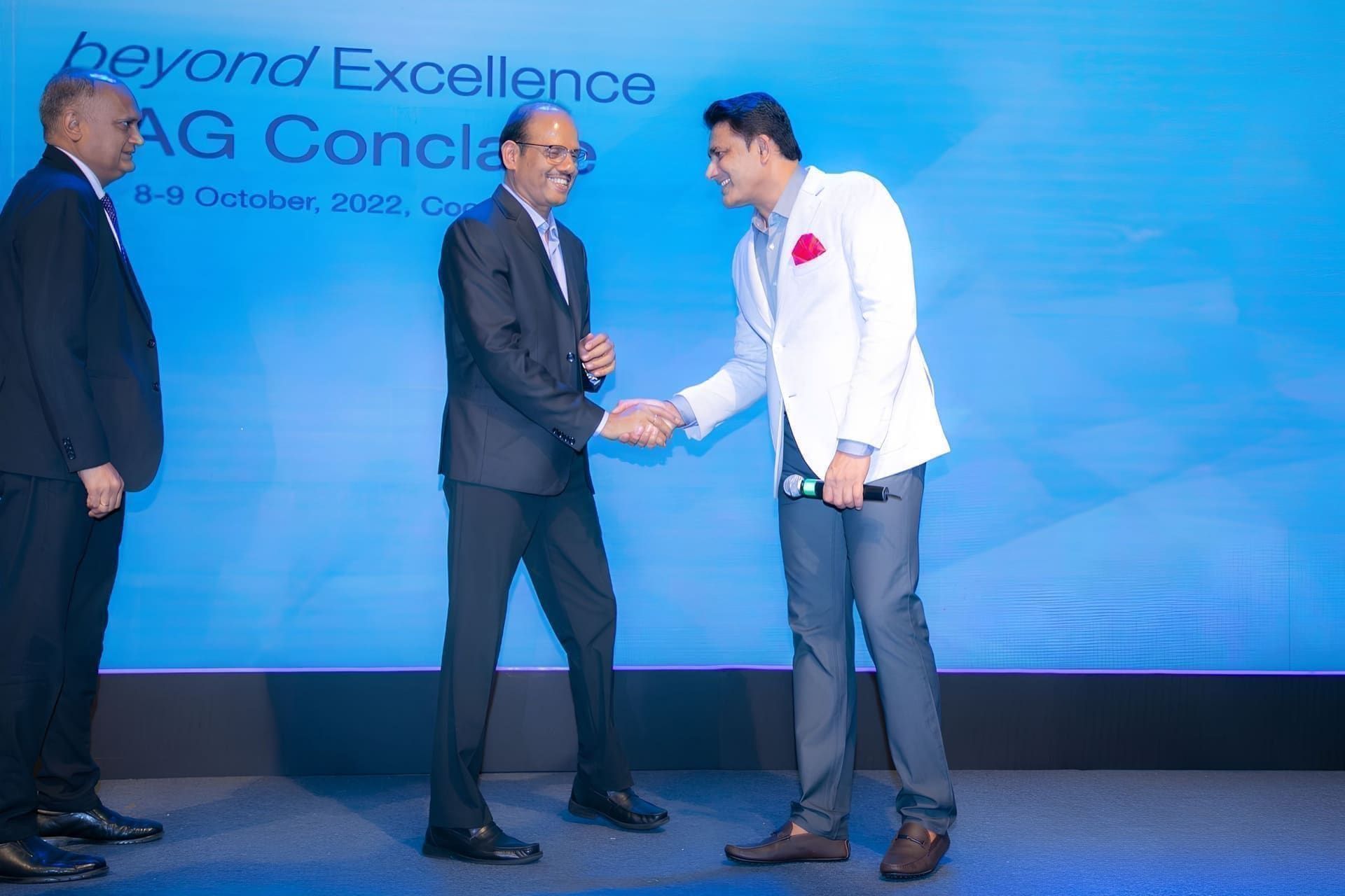 Executives shaking hands on stage at the Beyond Excellence AG Conclave
