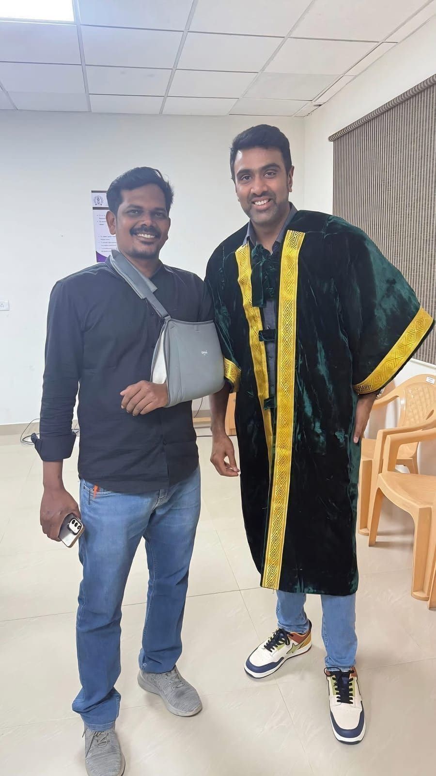 Two guests posing together with one wearing an academic gown