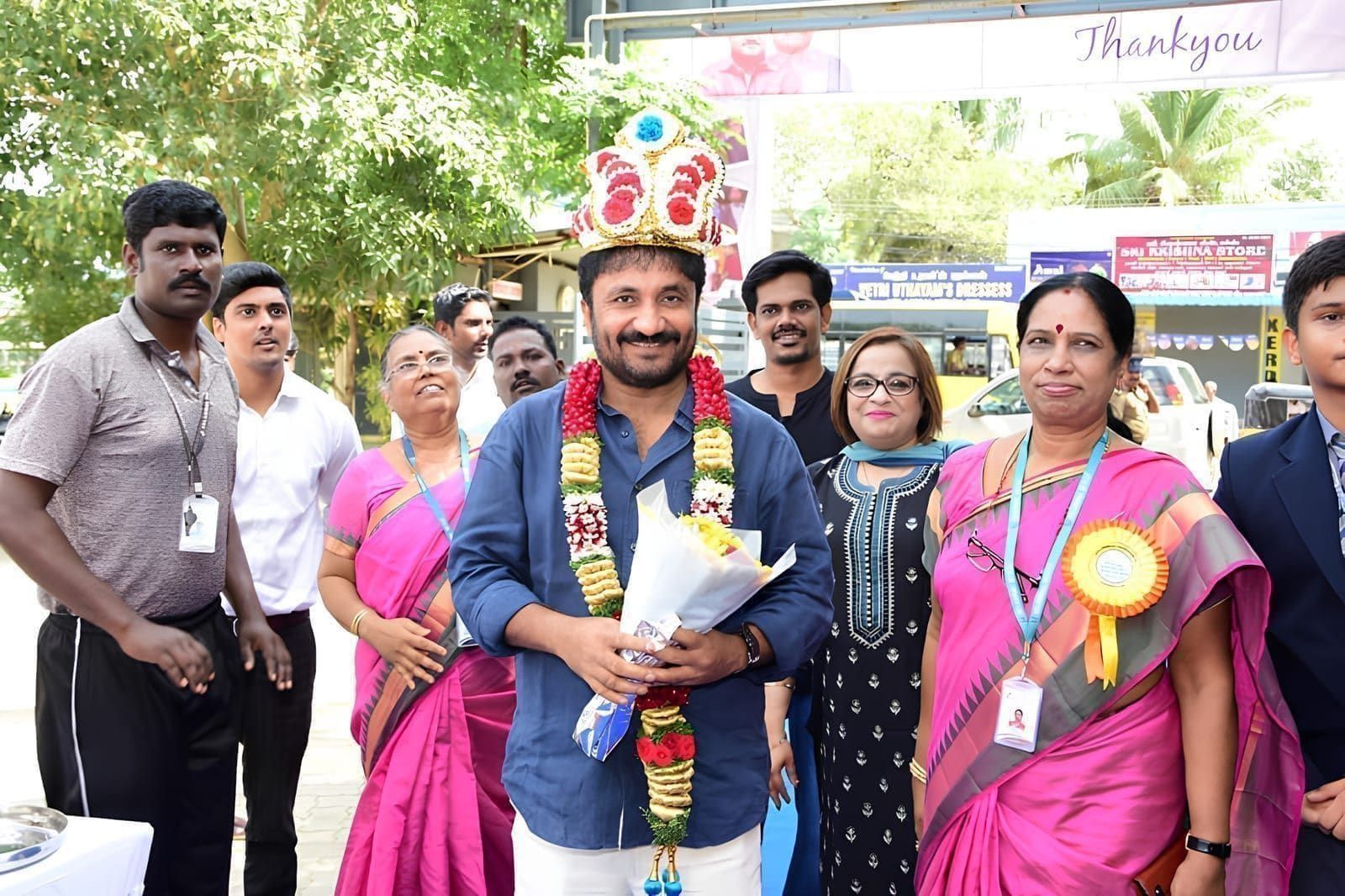 Garlanded guest holding a memento alongside school representatives