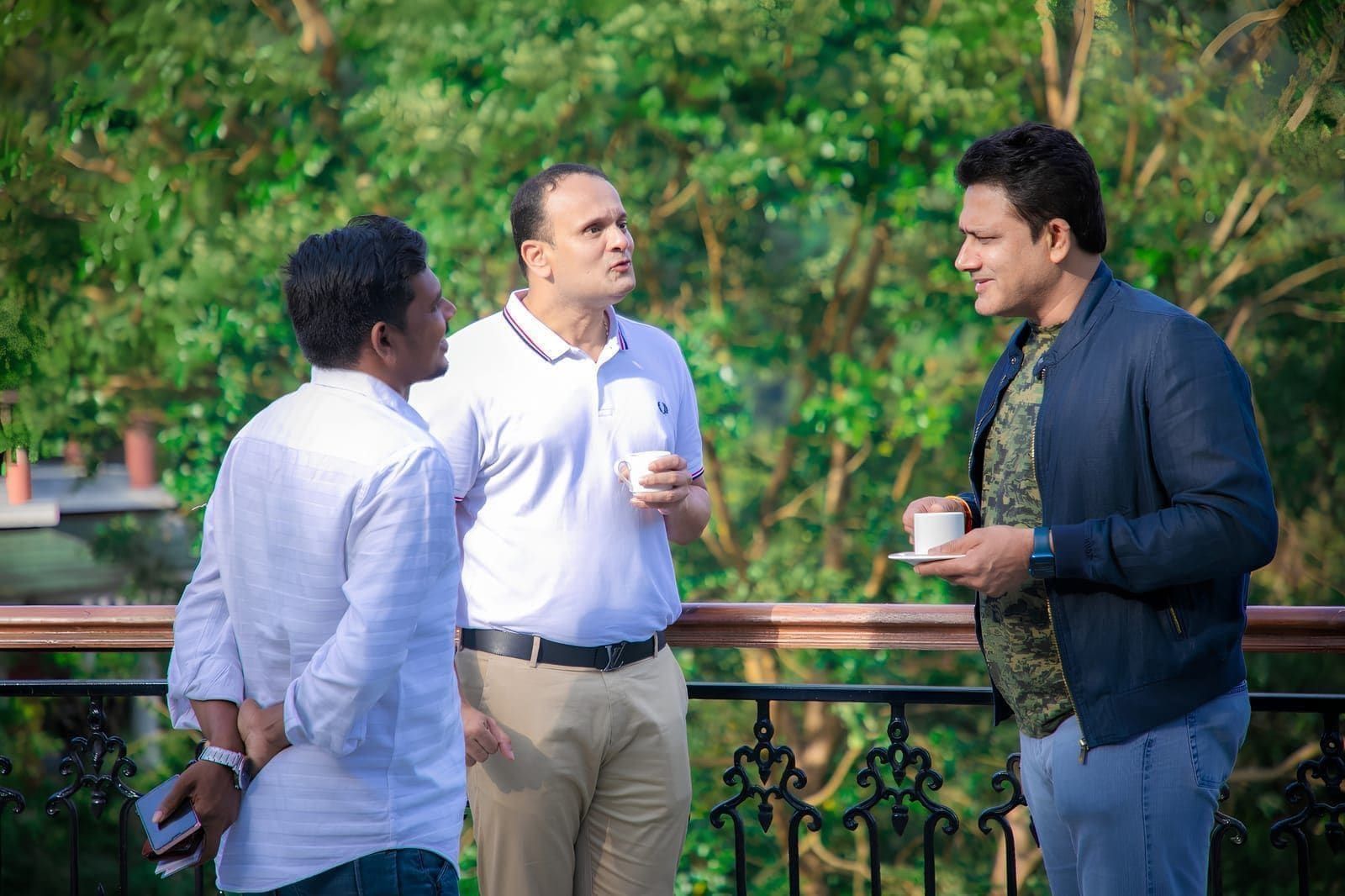 Three delegates talking over refreshments on a balcony