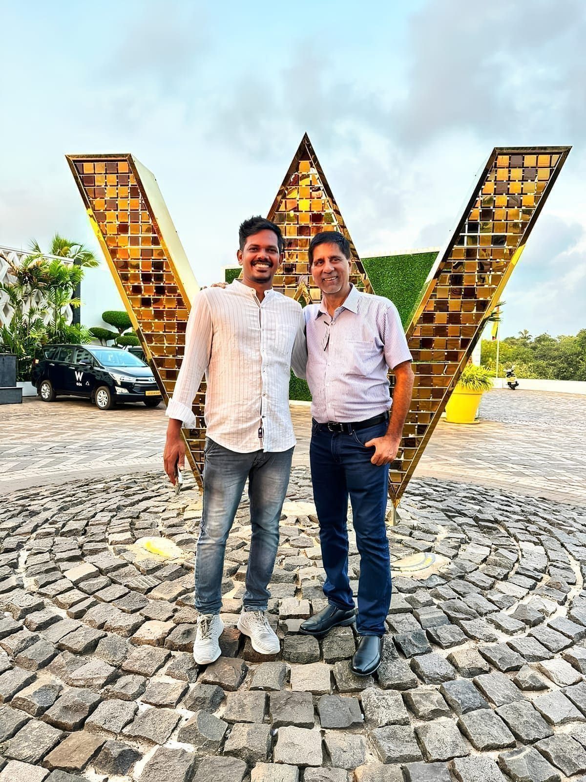 Two delegates posing outdoors in front of a large decorative W
