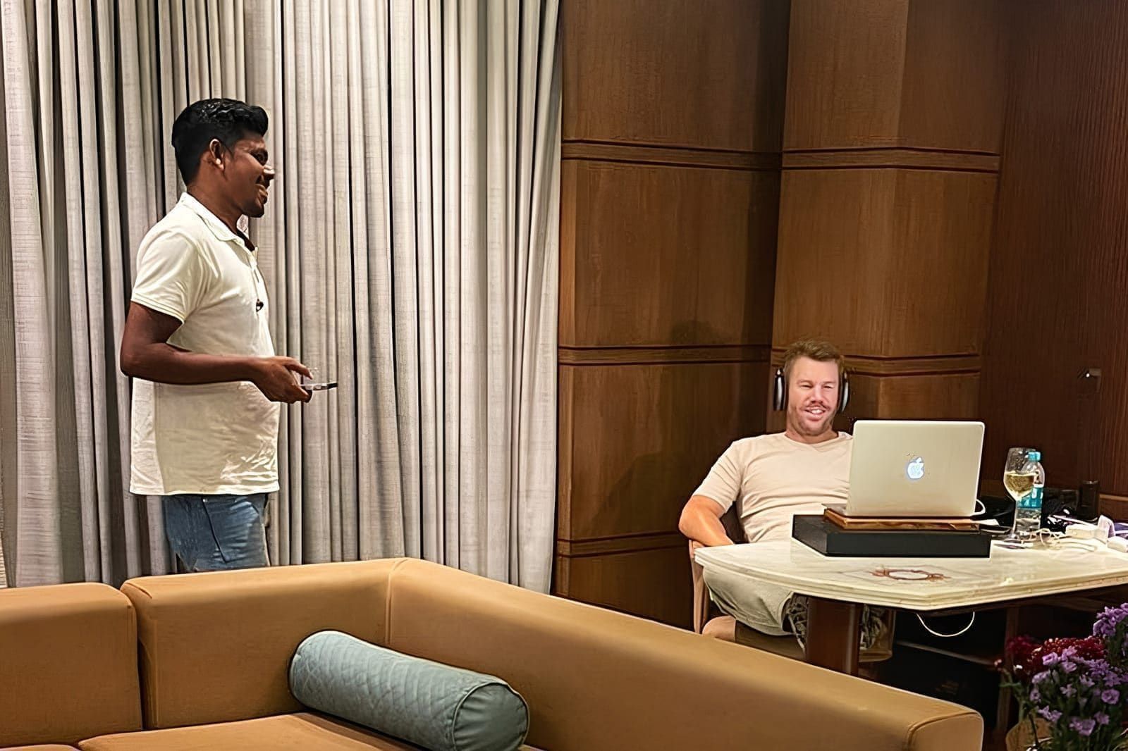 Guest standing beside a seated colleague working at a laptop