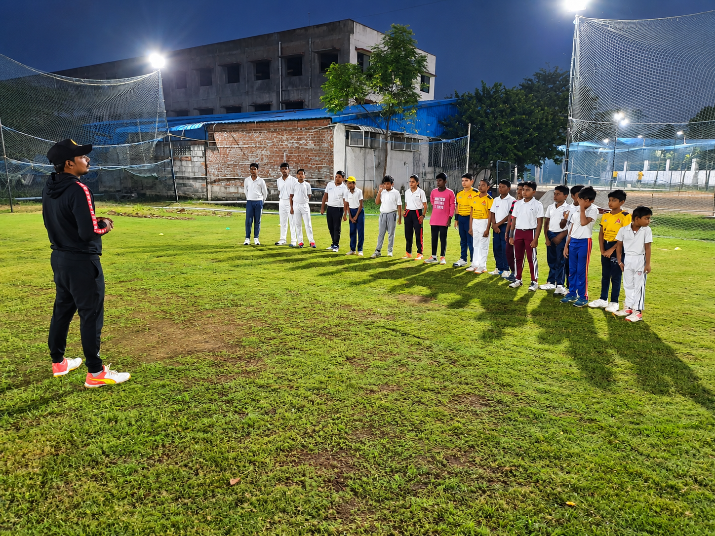 Coach briefing the junior academy squad at floodlit nets
